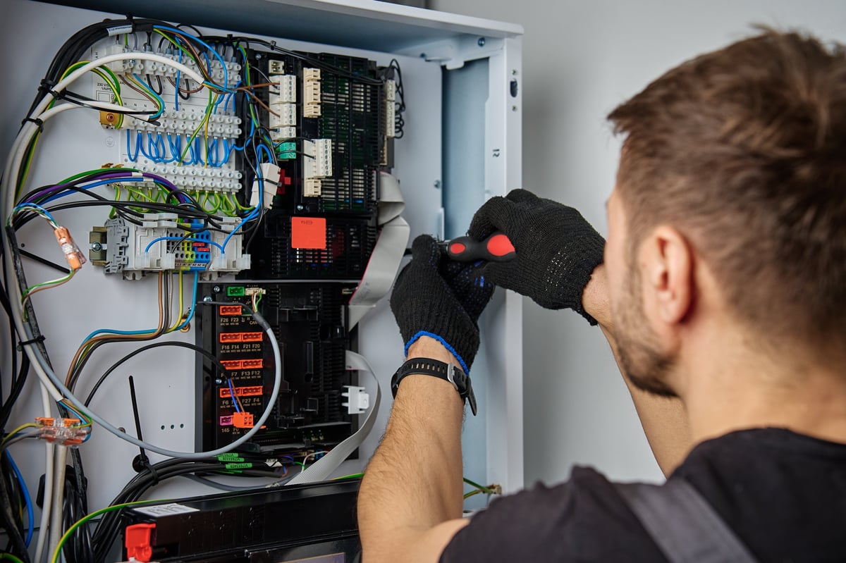 Technician working on internal wiring of heat pump, inspecting electrical connections.