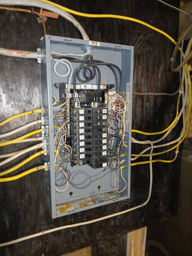 Open electrical panel with circuit breakers and wiring mounted on dark wall with yellow and gray conduit cables