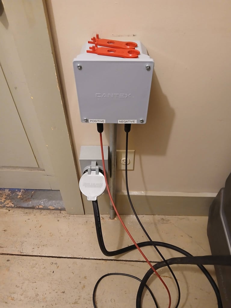 Gray electrical junction box mounted on wall with orange wire connectors on top and red and black wires running down to floor outlet